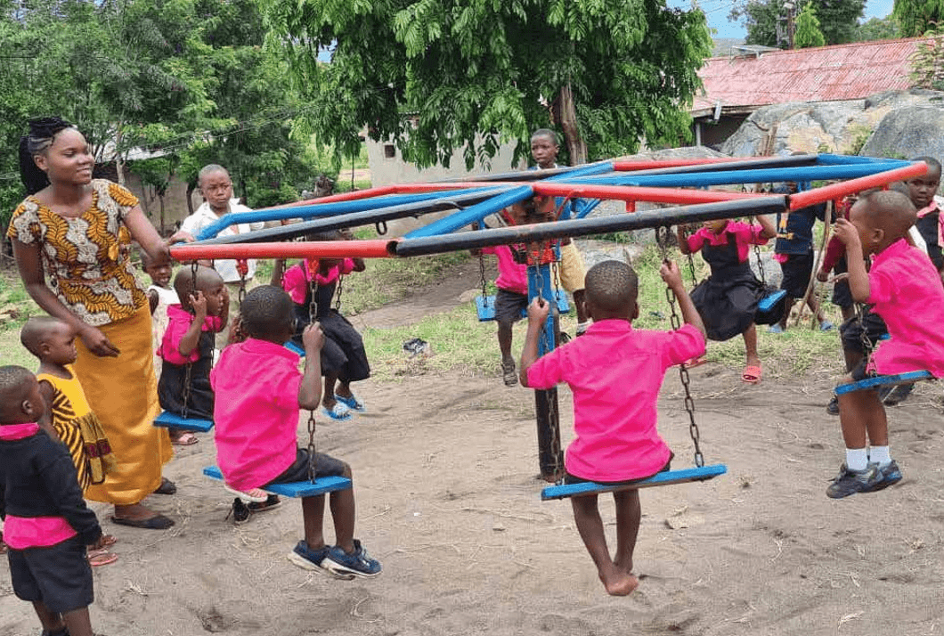 An ECD-trained childcare worker with toddlers on an FDC daycare playground spinner