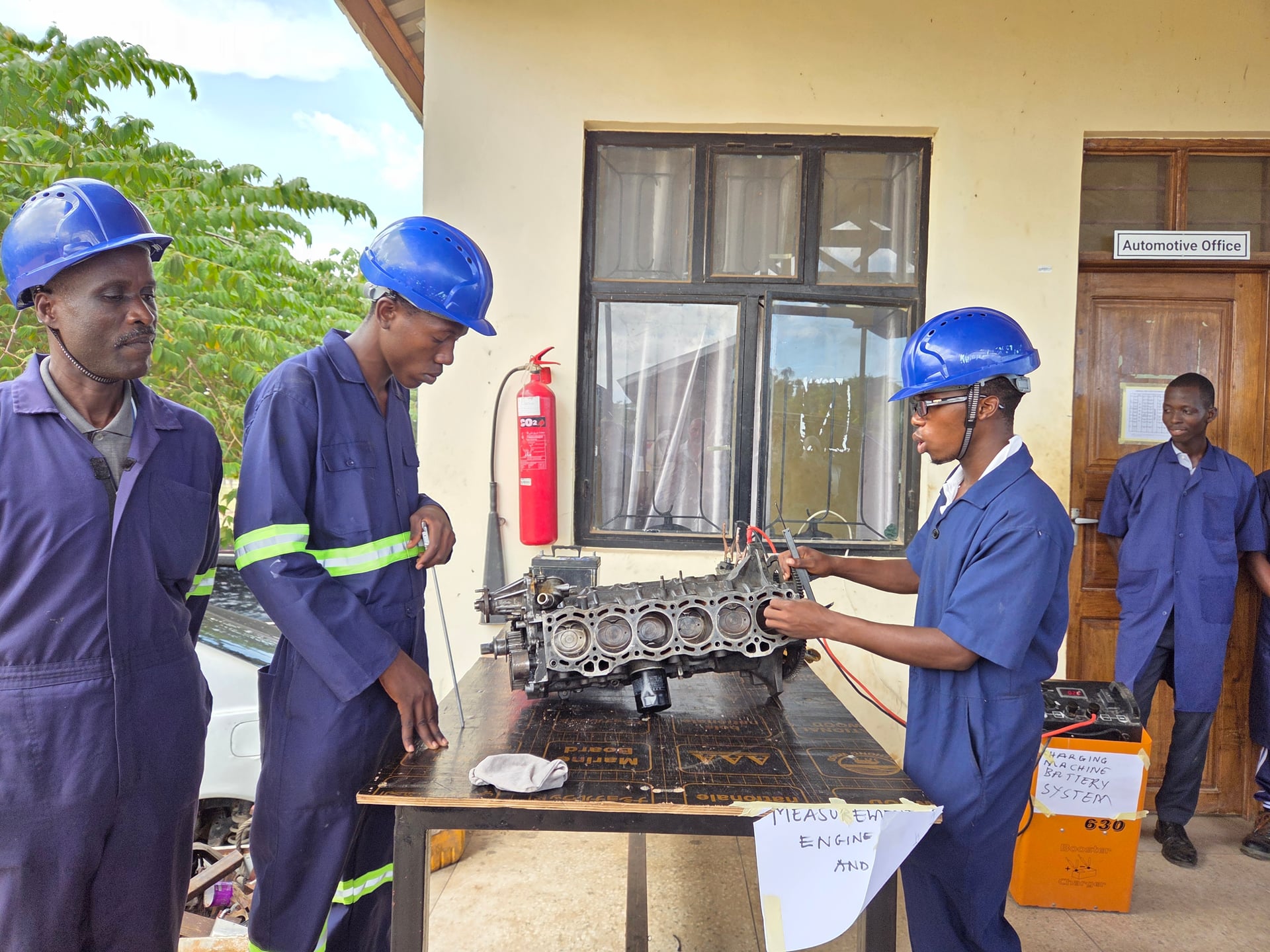 Automotive students in blue workshop overalls gathered outside an FDC vocational workshop